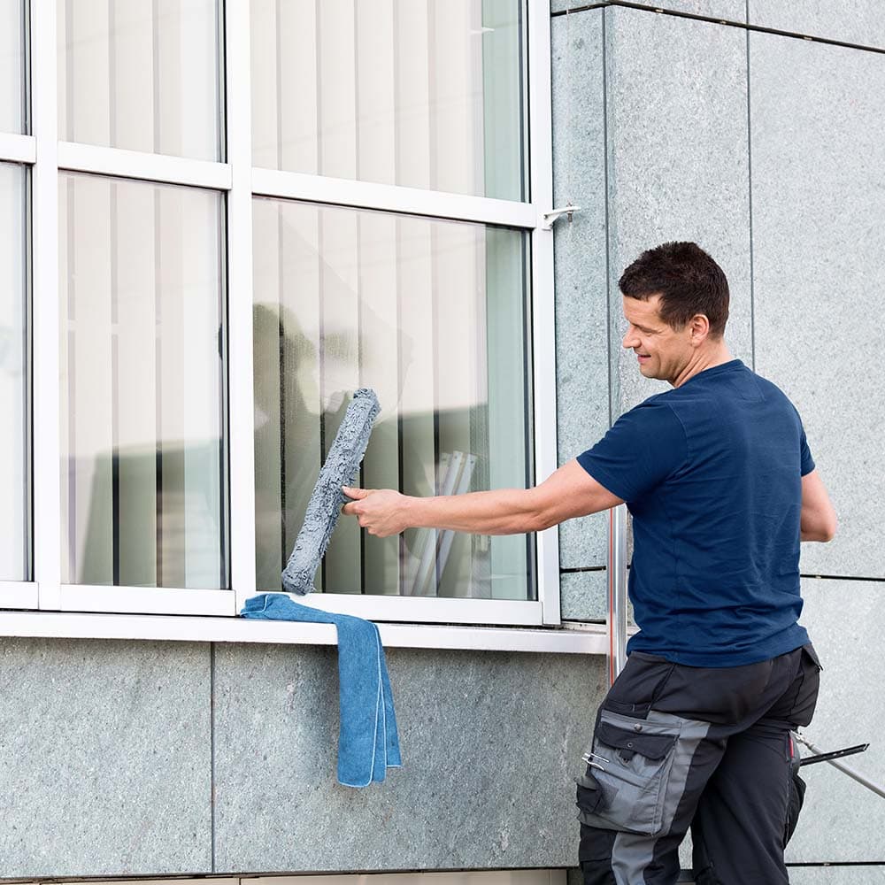 Fachgerechte Glasreinigung in Hamburg: Fensterputzer von Oxonio bei der Außenreinigung mit Einwascher und Poliertuch für ein streifenfreies Ergebnis