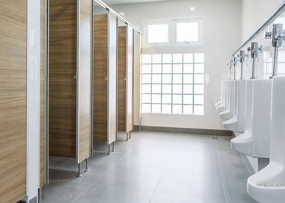 Sauberer Sanitärbereich mit Urinalen und Toilettenkabinen – gründliche Sanitärreinigung als Teil der Grundreinigung von Oxonio